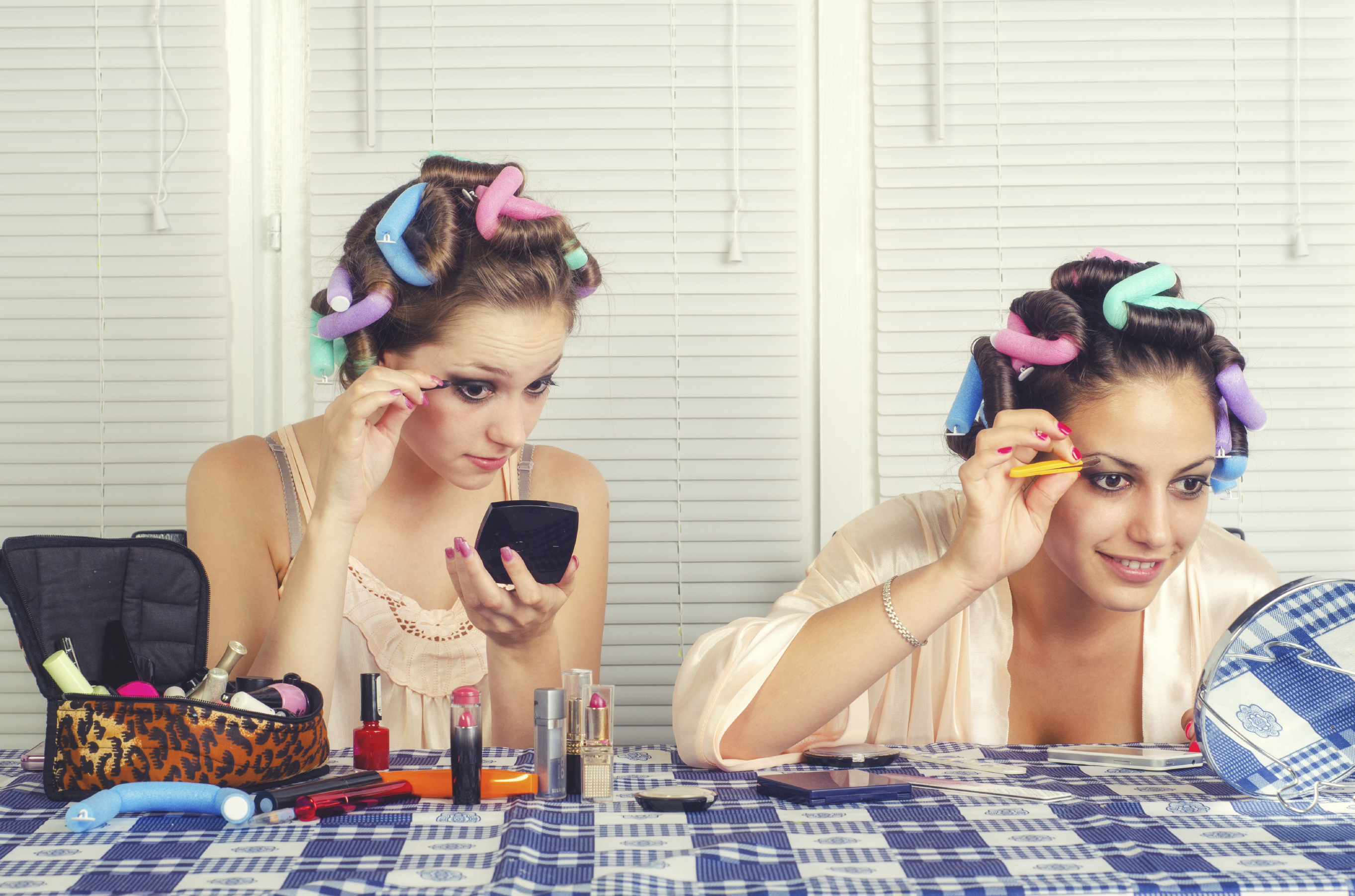 Two young housewives beautifying themselves at home